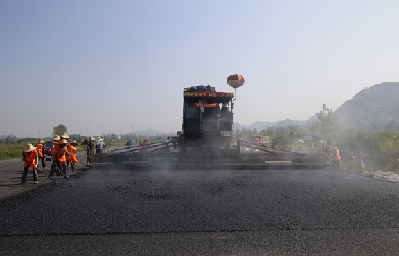 2019年8月，宜春經開區(qū)S311路面攤鋪現(xiàn)場，工友們輔助路面兩側的分料、補窩等作業(yè)